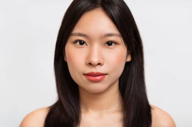 Headshot portrait of young asian woman posing looking at camera