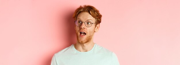Foto headshot portret van een verbaasde roodharige man met een bril open mond en hijgend kijkend naar de rechterbovenhoek