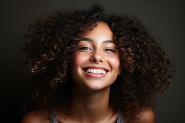 Headshot portret van lachend vrolijk meisje met krullend kapsel en witte brede glimlach op grijze achtergrond