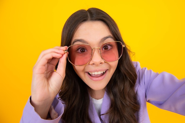 Headshot portret van schattige tiener kind meisje geïsoleerd op gele studio achtergrond draag zonnebril kijk naar camera kind probeer bril bij opticiens kind gezichtsvermogen behandeling concept