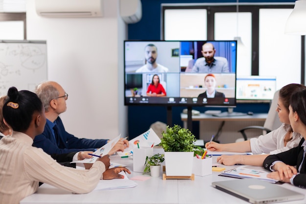 Headshot screen application view of remote multiracial employees talking on video call brainstorm together