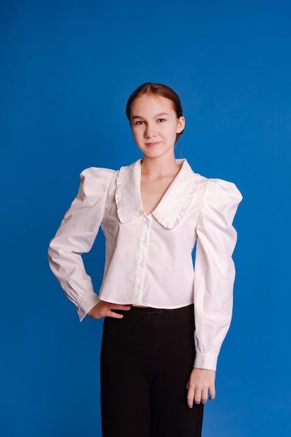 headshot teenage girl in white shirt looking at camera isolated light blue studio background