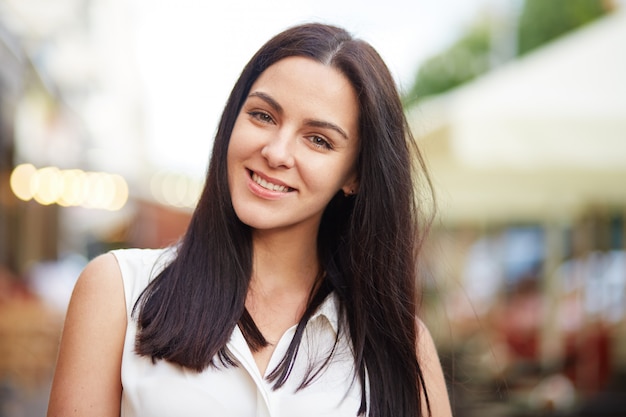 Headshot van brunette vrouw glimlacht vreugdevol