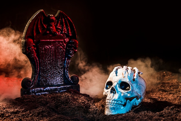 Photo headstone and skull between fog on ground