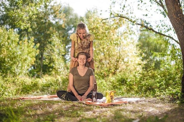 Healer applies her massage skills on her client on the grass.