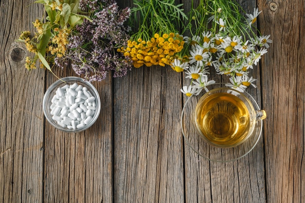 Healing herbs and bowl of pills on wooden table