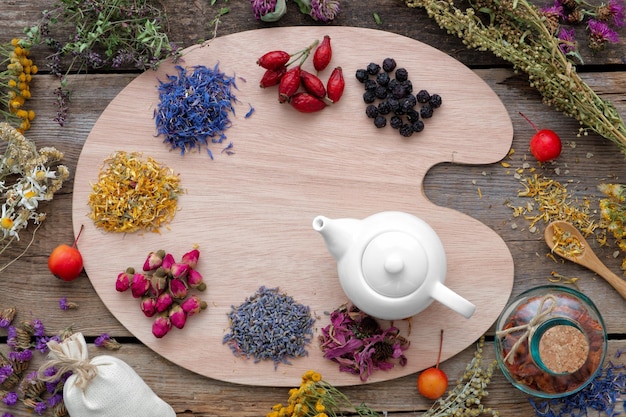 Healing herbs on wooden palette and tea kettle top view Herbal medicine concept