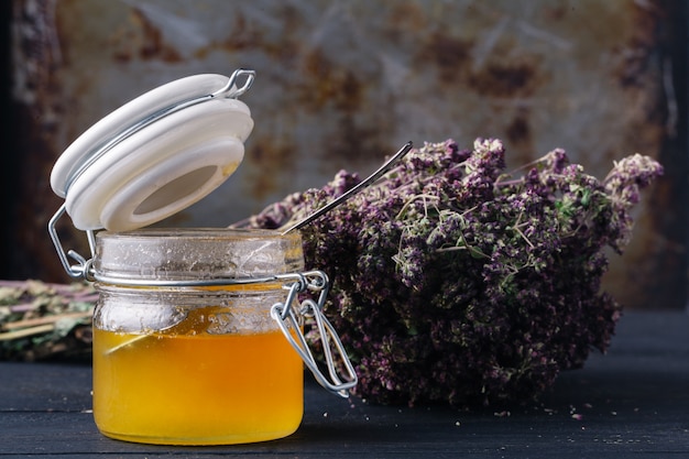 Healing honey with medicine herbs on dark wall
