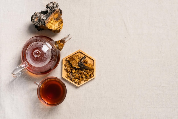 Healing tea from chaga birch mushrooms in a glass teapot and glass Organic drink antioxidant gray natural background