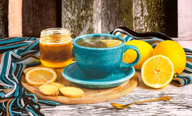 Healing tea with ginger root in a blue cup honey pieces of ginger and lemons woolen scarf