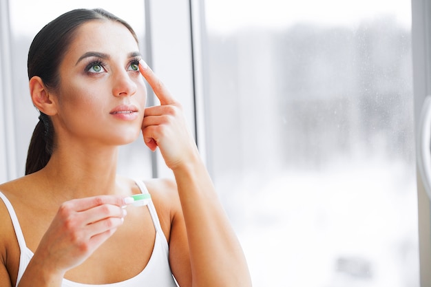 Health and beauty. beautiful young girl with green eyes holds contact lens on finger. eye care. good vision fresh view. high resolution