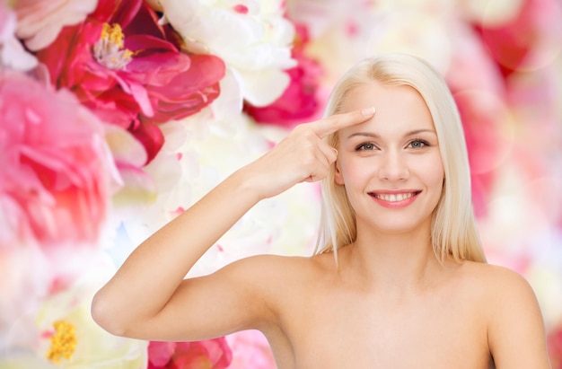 health and beauty concept - face of beautiful woman touching her forehead