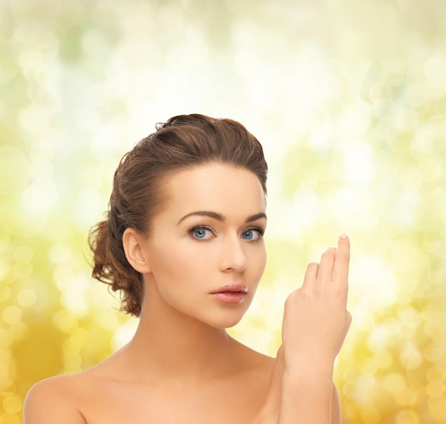 health and beauty concept - face and hands of beautiful woman with updo