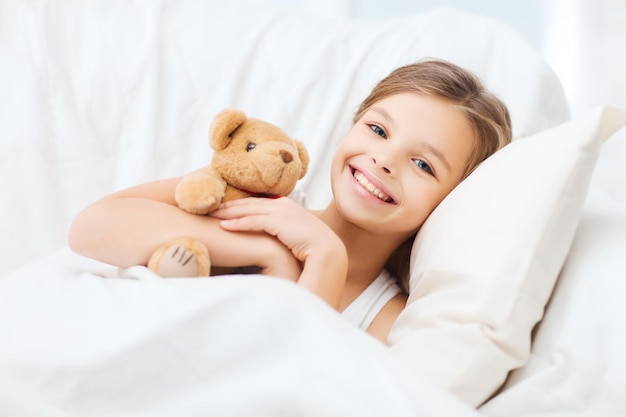 Photo health and beauty concept - little girl with teddy bear sleeping at home