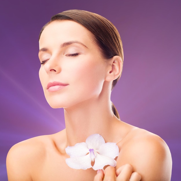 health and beauty concept - relaxed woman with orhid flower