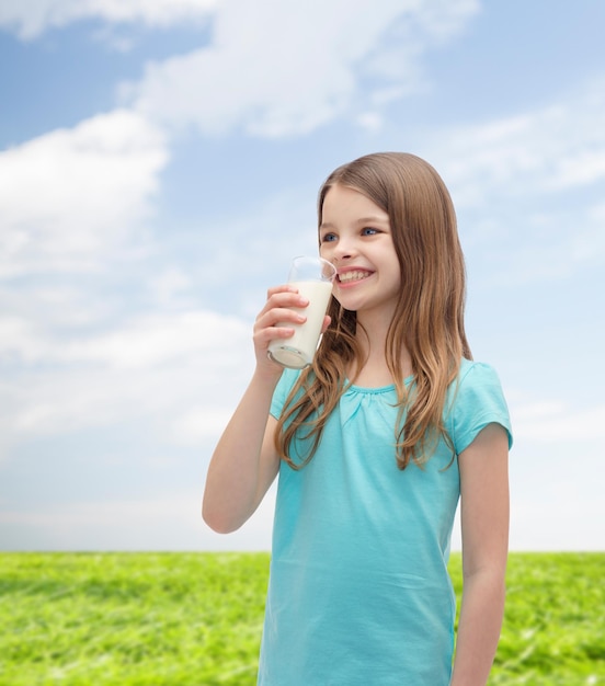 health and beauty concept - smiling little girl drinking milk out of glass