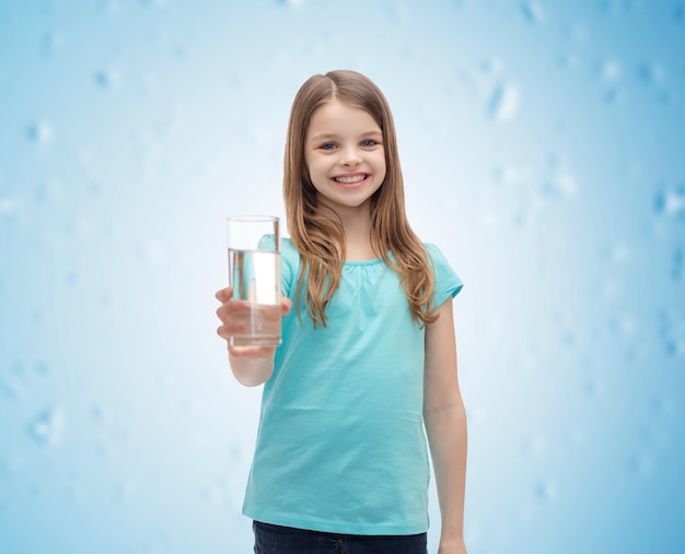 health and beauty concept - smiling little girl giving glass of water