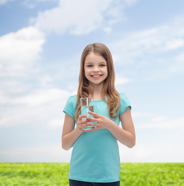 health and beauty concept - smiling little girl with glass of water