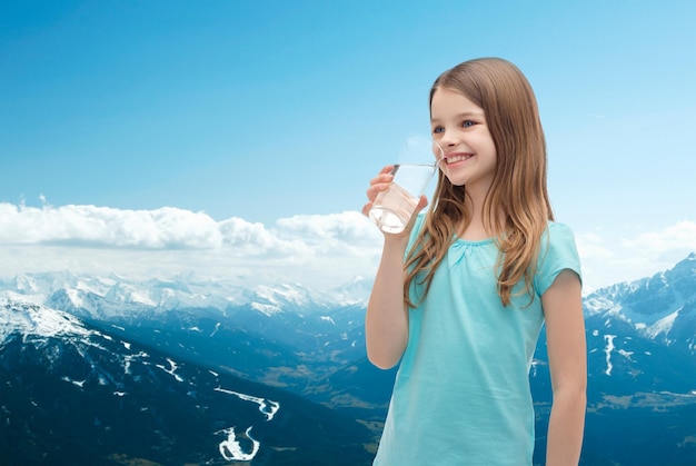 health and beauty concept - smiling little girl with glass of water