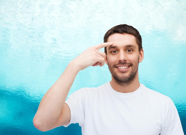 health and beauty concept - smiling young handsome man pointing to forehead