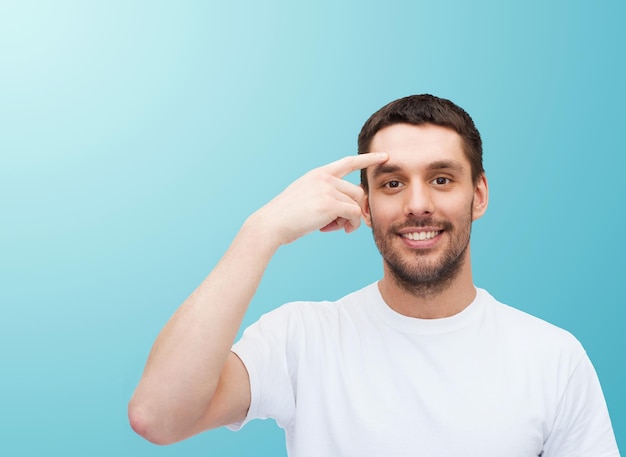 health and beauty concept - smiling young handsome man pointing to forehead