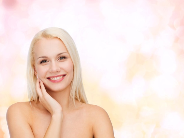 health and beauty concept - smiling young woman touching her face skin