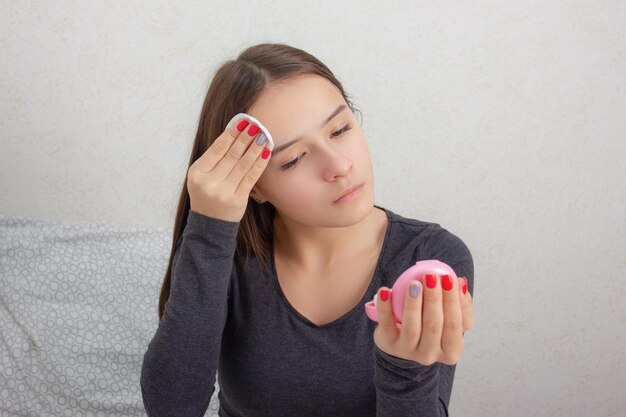 Health and beauty facial skin care a young girl rubs her face\
with a tonic nourishing lotion