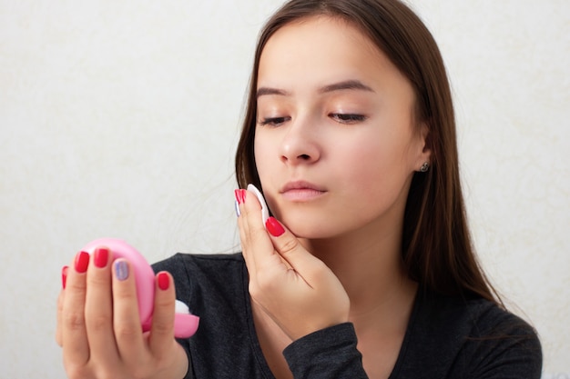 Health and beauty. Facial skin care. A young girl rubs her face with a tonic, nourishing lotion.