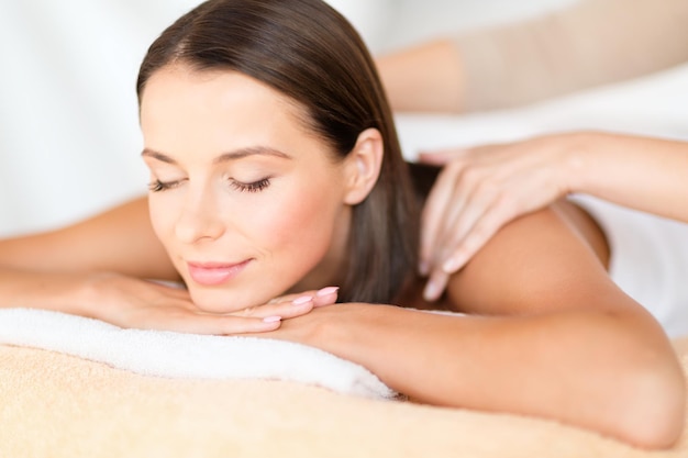 health, beauty, resort and relaxation concept - beautiful woman with closed eyes in spa salon getting massage