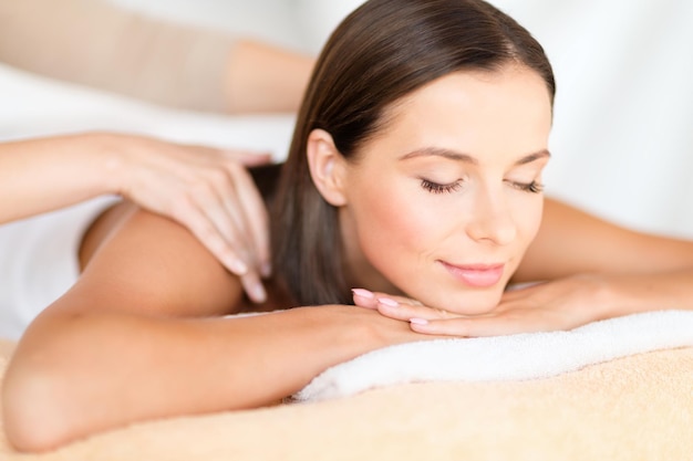 health, beauty, resort and relaxation concept - beautiful woman with closed eyes in spa salon getting massage