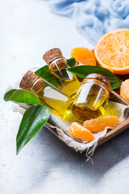 健康と美しさの静物の概念テーブルの上に緑の葉とオレンジ色の果物と小さなガラスの瓶に有機エッセンシャルタンジェリンマンダリンクレメンタインオイル