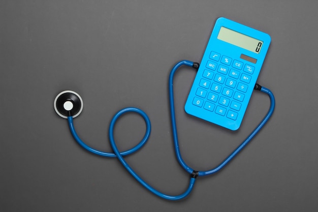 Health Care Concept. Calculator with a stethoscope on a gray