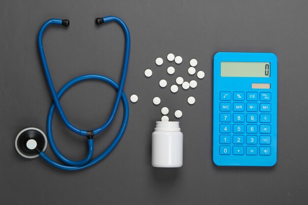 Health Care Concept. Calculator with a stethoscope, pills on gray