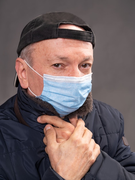 Концепция здравоохранения. Старший мужчина в защитной маске позирует в студии на сером фоне