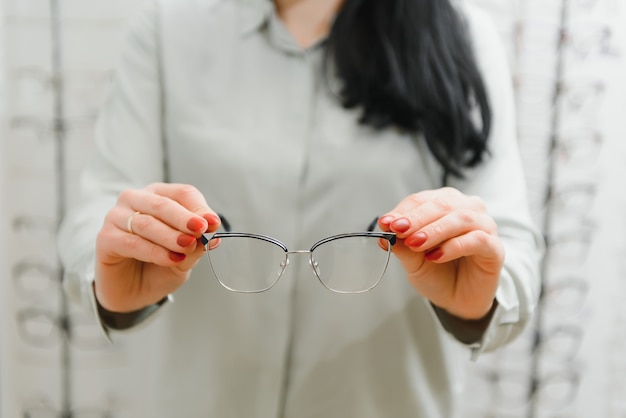 Health care, eyesight and vision concept - happy woman choosing glasses at optics store