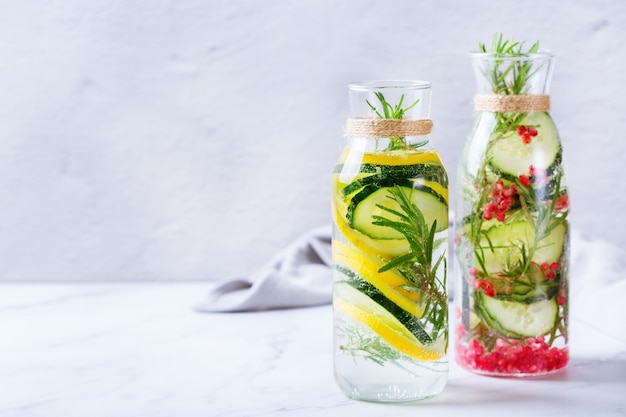 Health care, fitness, healthy nutrition diet concept. Fresh cool lemon cucumber rosemary pomegranate infused water, detox drink, lemonade in a glass jar for spring summer days.  Copy space background