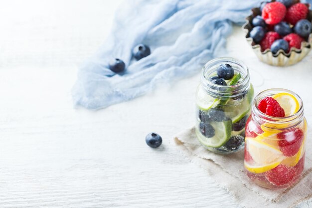 Health care fitness healthy nutrition diet concept Fresh cool lemon lime berries raspberry blueberry infused water cocktail detox drink lemonade for spring summer days Copy space background