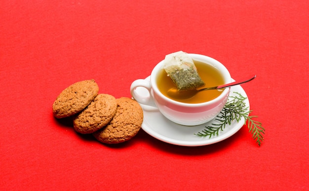 Health care folk remedies Herbal or green tea Ceramic cup hot fresh brewed tea beverage Warm winter beverage Gourmet delicious taste Cafe restaurant menu Cup of tea on red background close up