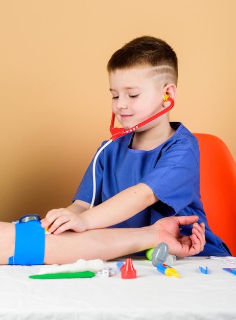 ヘルスケア子供の小さな医者は聴診器と医療ツールでテーブルに座る医学の概念血圧の測定医学検査医学教育少年かわいい子供将来の医者のキャリア
