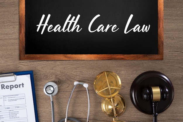 Надпись закона здравоохранения на доске, отчет, стетоскоп, весы и молоток