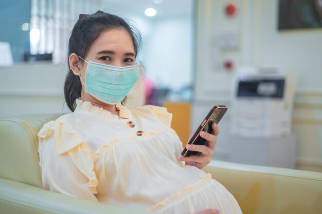 Health care pregnant wearing mask in public area protect\
coronavirus pregnant using smartphone