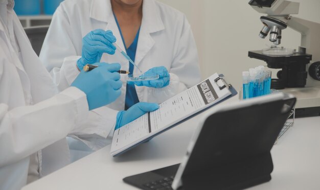 Photo health care researchers working in life science laboratory young female research scientist and senior male supervisor preparing and analyzing microscope slides in research lab