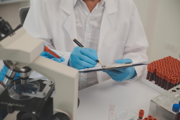 Photo health care researchers working in life science laboratory young female research scientist and senior male supervisor preparing and analyzing microscope slides in research lab