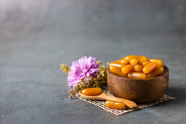 Health care vitamins in wooden bowl with flower