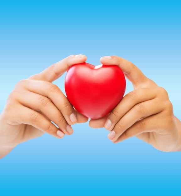 health and charity concept - close up of woman hands holding heart