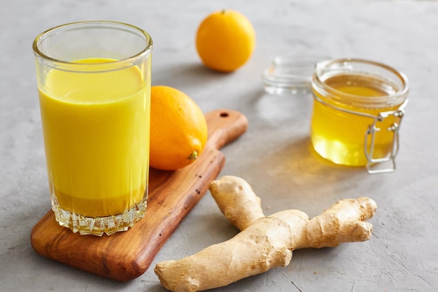 Концепция здоровья Золотое молоко, имбирь, лимонный мед на сером бетонном фоне. Средство от гриппа, повышающее энергию и здоровье.