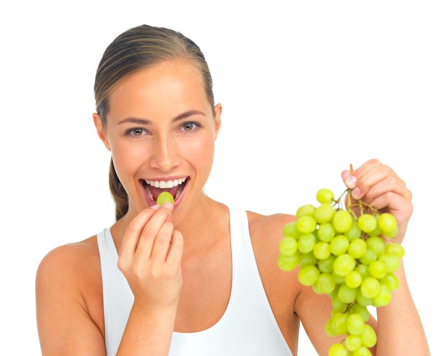 Foto dieta salutare e donna con uva in studio per uno spuntino sano nutrizione o desiderio benessere perdita di peso e ritratto di una giovane modella femminile che mangia frutta mentre è isolata da uno sfondo bianco