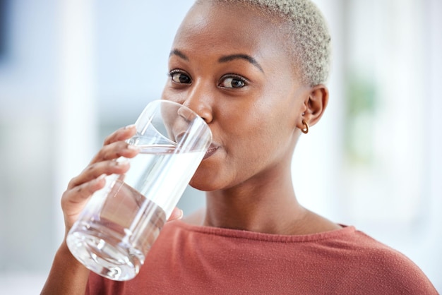 Health glass and portrait of a woman drinking water for hydration wellness and liquid diet Healthy h2o and headshot of young African female person enjoying a cold beverage or drink at her home