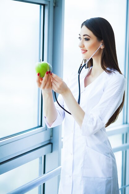 Salute. dieta sana. il dottore dietitian holding nelle mani apple e sorrisi verdi freschi. bello e giovane dottore.