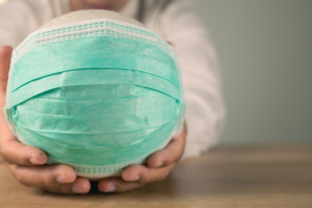 Health insurance in COVID concept A man holds a white ball with green medical mask Medium close up shot with copy space